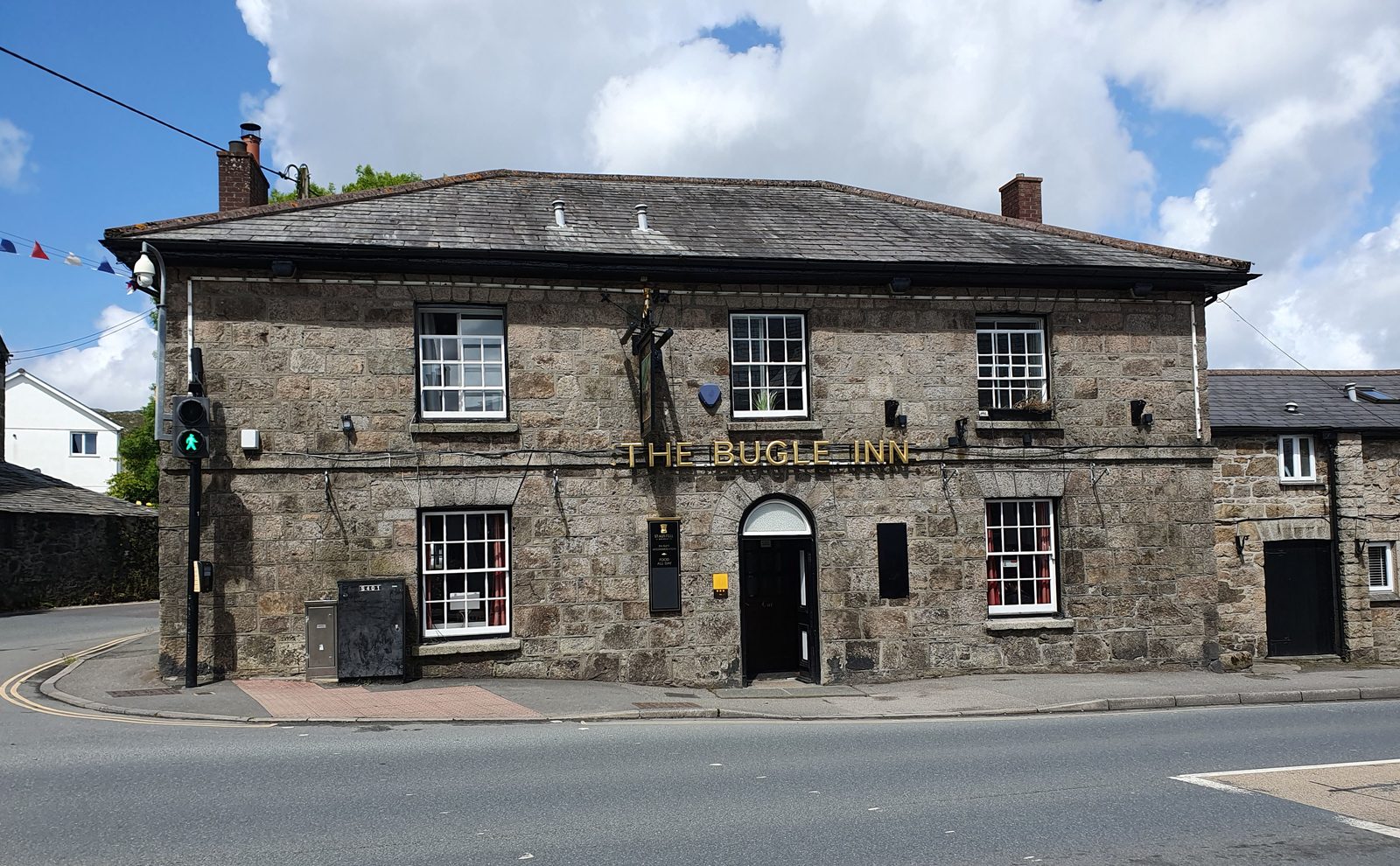 The granite frontage of The Bugle Inn on Fore Street — gold lettering above the door, est. 1840